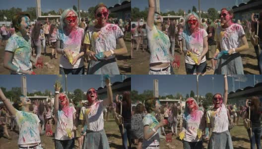 3个年轻的多民族女友在夏天的白天往胡里节上撒五颜六色的粉，欢笑着，友情概念，色彩概念高清在线视频素材下载