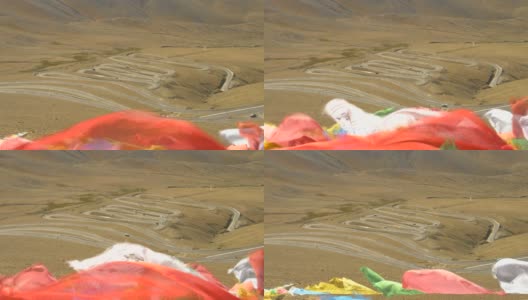 近距离观察:彩色的经幡飘扬在瓜拉山口蜿蜒的道路上高清在线视频素材下载