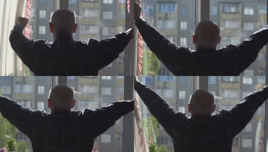 一个老人的剪影拉开窗帘，站在大窗户前高清在线视频素材下载
