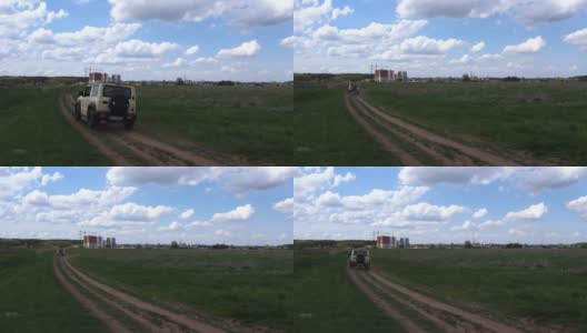 夏日里，在空旷的乡间小路上，一辆小型四轮驱动汽车沿着田野附近的小路行驶，看着草原上尘土飞扬的道路高清在线视频素材下载