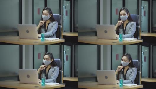 亚洲女雇员戴着口罩使用笔记本电脑在商业办公室工作与同事保持社交距离保护冠状病毒或covid-19爆发大流行。职场新常态政策高清在线视频素材下载