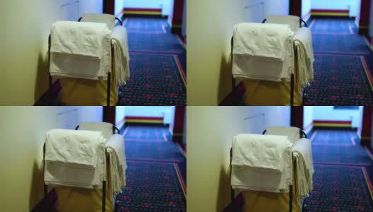 酒店服务员的手推车停在房间前面，干净的毛巾和浴衣已准备好更换和整理房间高清在线视频素材下载