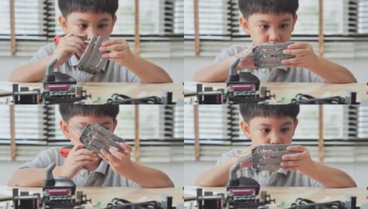 男孩在家里用电脑制作和编程，并制作一个机器人手臂作为学校的科学项目。他对自己的工作非常满意。教育、儿童、技术、科学是人们的理念高清在线视频素材下载