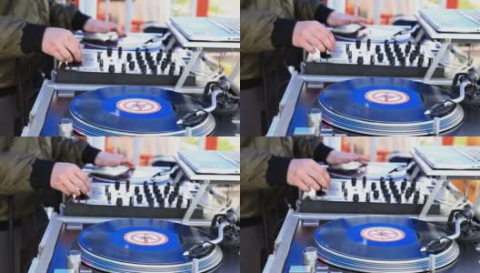 DJ播放音乐，在一个转盘上刮黑胶唱片在露天派对。手的特写镜头。高清在线视频素材下载