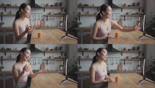 健康的亚洲女性在智能手机上用LED环灯直播视频，手里拿着新鲜的果汁。植入式广告的概念高清在线视频素材下载