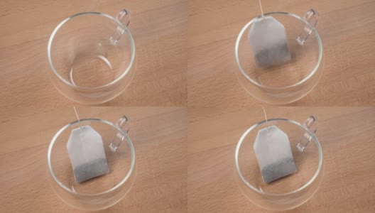 用细绳系上标签的茶袋落入一个透明的空杯子里高清在线视频素材下载