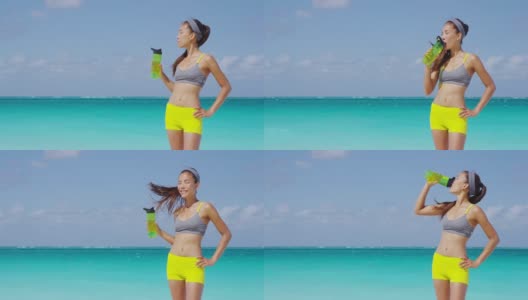 健身跑步的女人喝水或运动瓶的能量饮料。在炎炎夏日的沙滩上，女运动员在跑步时休息，补充水分。健康积极的生活方式。高清在线视频素材下载