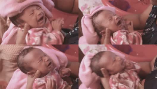 新生婴儿在洗澡。美丽的新生男婴特写(6天大)躺在母亲的膝盖在产前医院。孩子裹着婴儿毯(暖和的衣服)微笑着看。他的母亲安慰和休息她的婴儿。高清在线视频素材下载