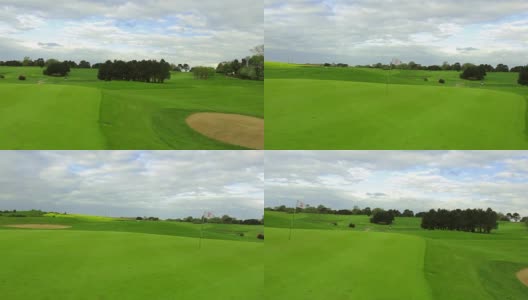 在一个晴朗多风的日子里，一个绿色的高尔夫球场，洞和旗子。高清在线视频素材下载