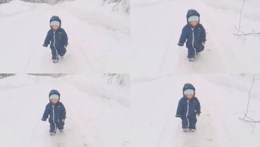 在冬季公园散步的小男孩。小朋友在雪地上踏出第一步。高清在线视频素材下载