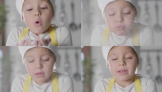 一个小女孩打扮成专业厨师在厨房里玩面粉，弄脏了她的手，开心地笑了。高清在线视频素材下载