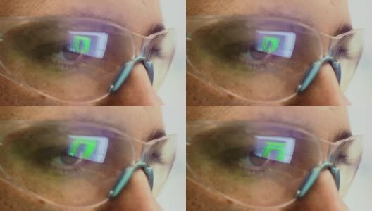 一个高加索技术员的眼睛的特写镜头与反射的电脑屏幕在他的保护眼镜在一个室内办公室高清在线视频素材下载