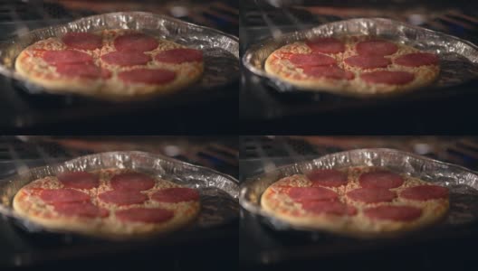 在家里用电炉自制意大利圆形披萨，美味的披萨香辣的东西。厨师用辣意大利腊肠、磨碎的马苏里拉奶酪和帕尔马干酪制作披萨。美味的披萨在烤箱中烹饪高清在线视频素材下载