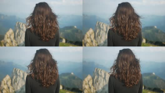 长头发的徒步旅行者女孩在奥地利萨尔兹卡默古特的沙夫伯格山观看史诗般的景色。60帧/秒的慢速镜头，在阿尔卑斯山的山峰上吹着风。高清在线视频素材下载