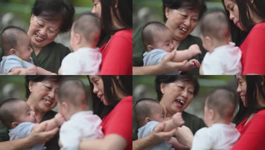 一位年长的亚洲华人妇女和她的双胞胎儿子孙子在他们家的前院和她的女儿一起玩高清在线视频素材下载
