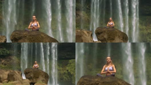 坐着的女人在水墙旁边的岩石上冥想瑜伽高清在线视频素材下载