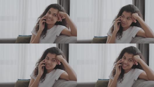 美丽的年轻的非洲裔美国女士在她的手机上聊天，听着一个电话，脸上洋溢着喜悦的微笑高清在线视频素材下载