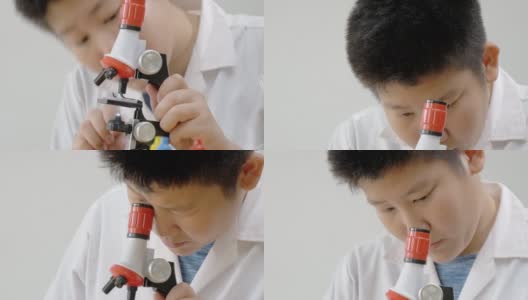 亚洲男孩穿着实验服，在学校实验室使用显微镜进行测试，教育的生活方式理念。高清在线视频素材下载
