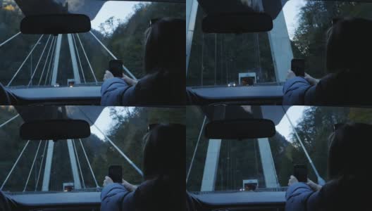 汽车在桥上。手放在方向盘和仪表盘上，白天开车过桥。一个女孩从车里拍摄道路的景色。慢动作高清在线视频素材下载
