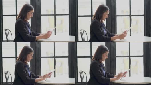 亚洲女商人用数码平板电脑喝咖啡在咖啡店或餐厅的窗户上休息一下高清在线视频素材下载