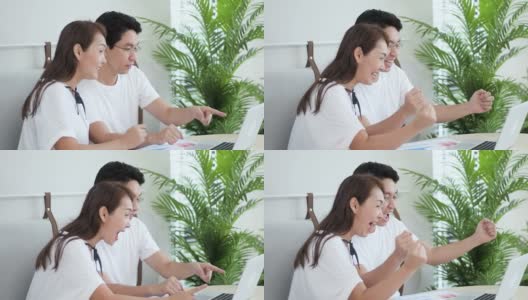 慢动作激动的亚洲夫妇使用笔记本电脑，获奖者高清在线视频素材下载