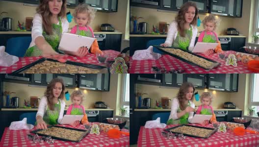 快乐的家庭女孩烤饼干，看着桌上的电脑高清在线视频素材下载