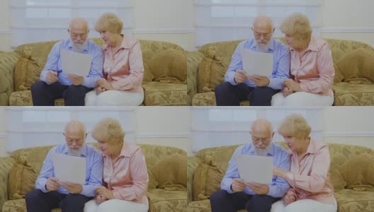 一对老年夫妇坐在客厅的沙发上查看房租账单高清在线视频素材下载