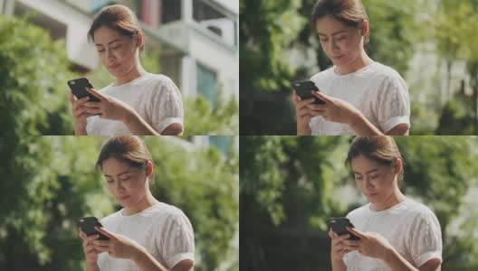 亚洲美女正在使用智能手机上网和聊天的朋友在花园里高清在线视频素材下载