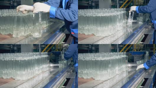 工厂员工正在把玻璃瓶子放到传送带上高清在线视频素材下载