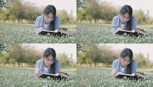 年轻的亚洲女孩在公园看书高清在线视频素材下载