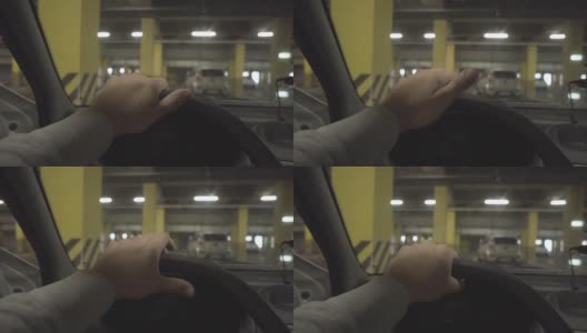 一名男子正坐在一辆车里，摄像机从一辆车里拍摄了一幅购物中心停车场内部的画面。高清在线视频素材下载