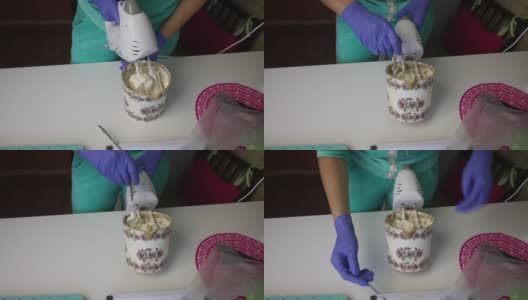 一个女人用搅拌机在一个容器里准备棉花糖。用勺子从搅拌器中取出。高清在线视频素材下载