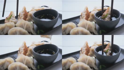 黑色的盘子上放葱汁煎饺，背景颜色较深。高清在线视频素材下载