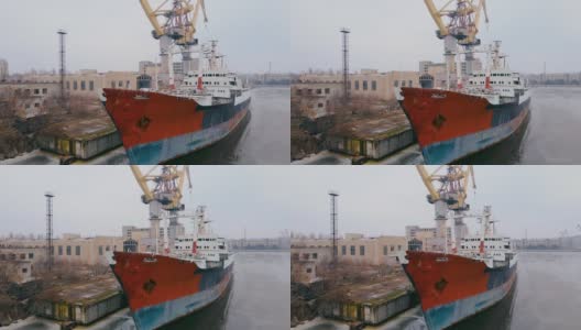 废弃的沉没锈迹斑斑的船多年停泊在港口，有多吨位起重机和商业建筑高清在线视频素材下载