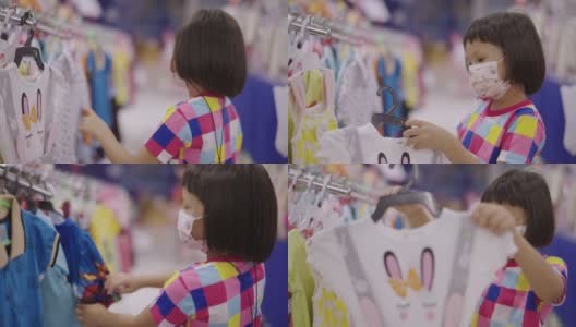 一个亚洲小女孩戴着口罩在当地的超市里走着，看着货架上的产品。高清在线视频素材下载