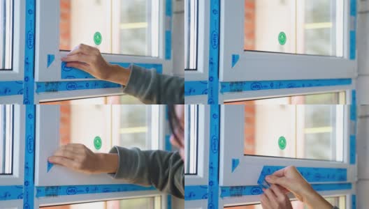 在一处私人住宅中，Veka从WHS公司的新塑料窗户上撕下了蓝色的保护性管道胶带。女人的手撕掉了胶带。2021年10月29日，俄罗斯卡卢日高清在线视频素材下载