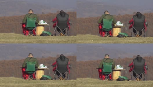 两名认不出的男子在山上野餐，欣赏秋天五彩山的景色高清在线视频素材下载