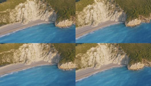 鸟瞰希腊爱奥尼亚岛莱夫卡达美丽的米洛斯沙滩。夕阳金色的阳光和原始的海浪打破了蓝绿色的大海在岸边高清在线视频素材下载