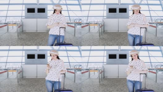 快乐的女性旅客站在机场大厅，用她的手提箱使用手机高清在线视频素材下载