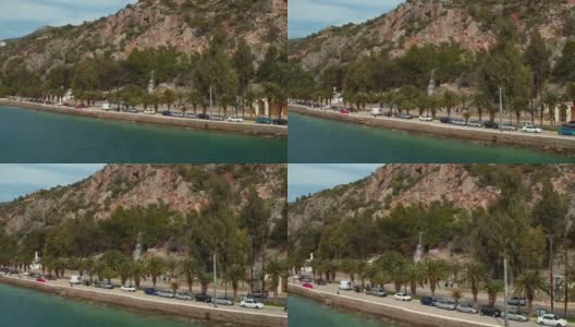 空中-劳特拉基-希腊，向前走一条有棕榈树和瀑布的沿海道路高清在线视频素材下载