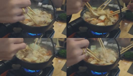 在一家日本餐馆里，餐桌上的每个人都用筷子从涮锅里拿食物。高清在线视频素材下载