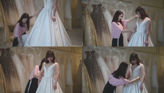 亚洲华人女婚纱店老板正在为顾客测量新娘的体型，为顾客量身定制婚纱高清在线视频素材下载