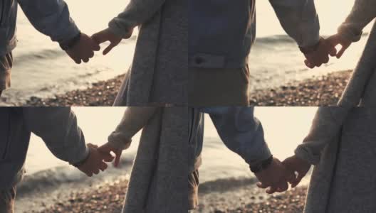 近距离拍摄的男人和女人的手，夫妇俩正站在海边高清在线视频素材下载