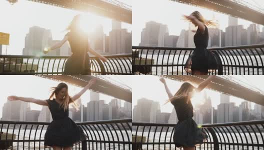 美丽兴奋的旅行者女孩在布鲁克林大桥的河堤上旋转，手臂在空中举起高清在线视频素材下载