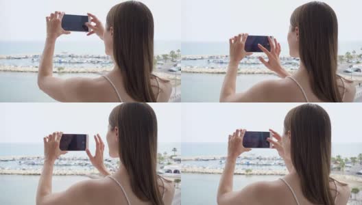 一个女人在阳台上用手机。女性喜欢看海，用手机慢动作拍照高清在线视频素材下载