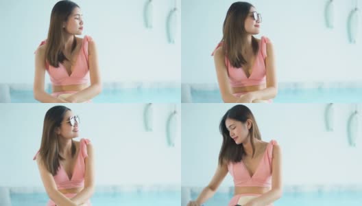 4K视频穿着比基尼的美女戴着太阳镜坐在泳池边高清在线视频素材下载