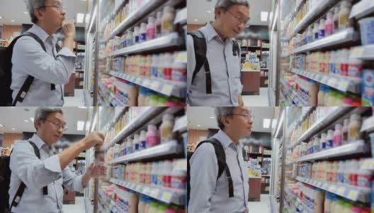 老人在超市买食物和饮料。一位老人在当地超市购物。他正拿着瓶子，阅读营养标签。购物,快乐,人的生活方式,健康和医学。食品杂货店购物。老年人购物高清在线视频素材下载