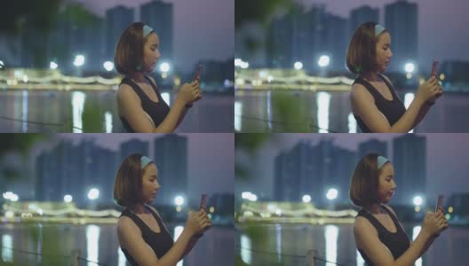 一名亚洲女性晚上在公园跑步后使用智能手机高清在线视频素材下载