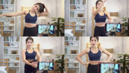 20多岁的年轻亚洲女性穿着运动服对着镜头说话，并在网上解释健身教程。健康女孩博客在家里的客厅。教授网上健身课的概念高清在线视频素材下载