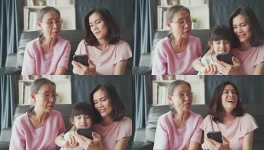 亚洲家庭的孩子、母亲、祖母在客厅里用智能手机一起玩互联网，带着幸福和微笑。快乐活动科技生活方式手机使用概念。高清在线视频素材下载